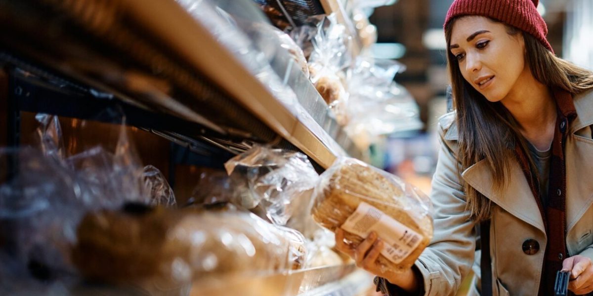 Young,Woman,Choosing,Bread,While,Buying,Groceries,In,Supermarket.
