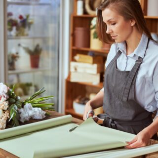 Close,Up,Of,Female,Florist,Hands,Cutting,Color,Wrapping,Paper