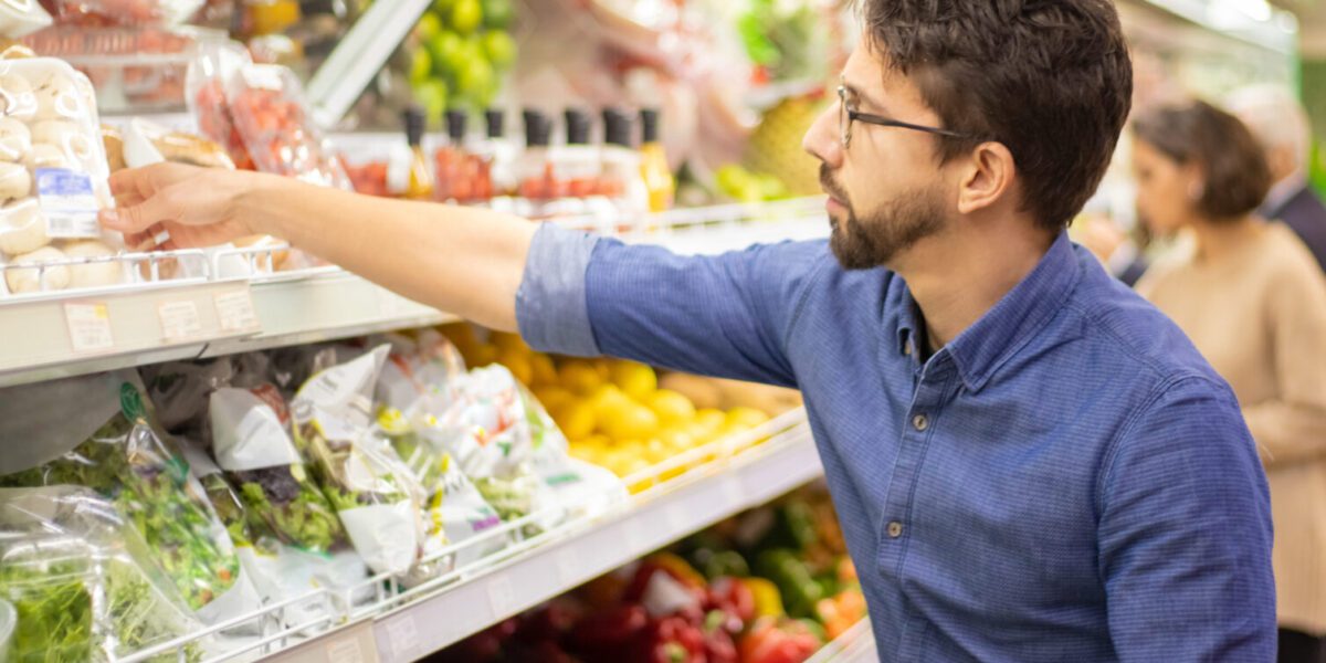 man pakt groente uit schap un supermarktflowpack (food)