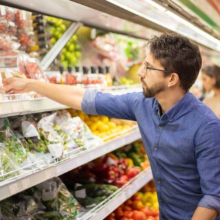 man pakt groente uit schap un supermarktflowpack (food)