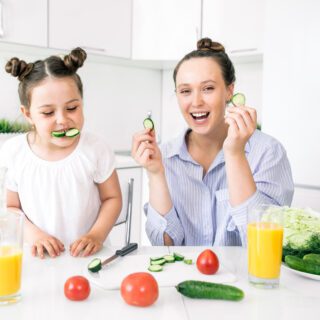 Moeder met dochter die komkommer eten krimpfolie food